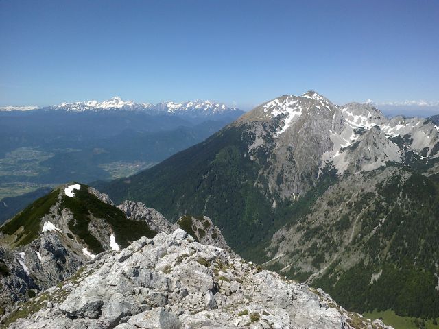 Razgled z vrha na Julijske alpe v daljavi in Stol (desno)