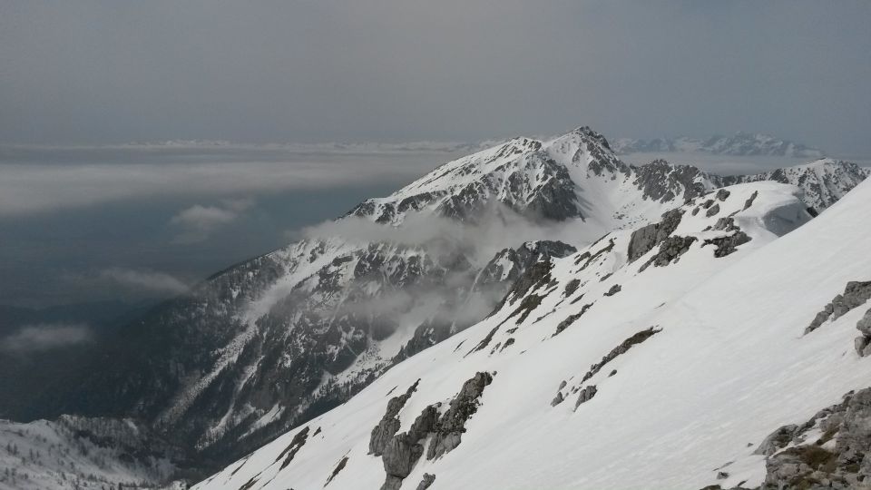 Razgled z vrha Vrtače na Stol (v ospredju) in Julijske Alpe (v ozadju)