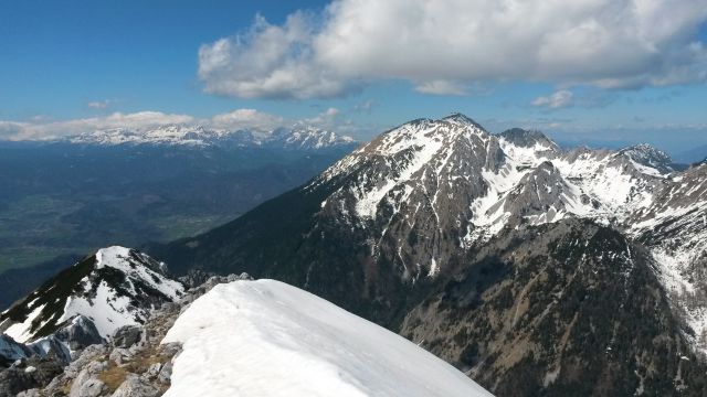 Razgled z vrha Begunjščice na Julijske Alpe (levo v ozadju) in Stol (desno)